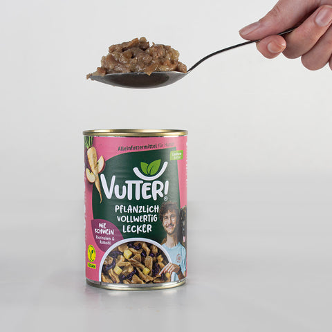 Aus einer Vutter! Nassfutterdose wie Schwein in Zusammenarbeit mit Dr. Karim Montasser wird mit einem Löffel etwas Nassfutter herausgenommen. Oben rechts in der Ecke sieht man die Hand, die den Löffel hält.