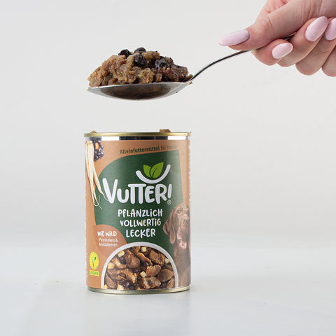 Ein Esslöffel unseres veganen Nassfutters wie Wild von Vutter! wird aus der Dose genommen