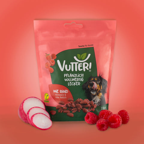 Neben einer Tüte veganen Leckerli wie Rind von Vutter! liegen roter Rettich und Himbeeren